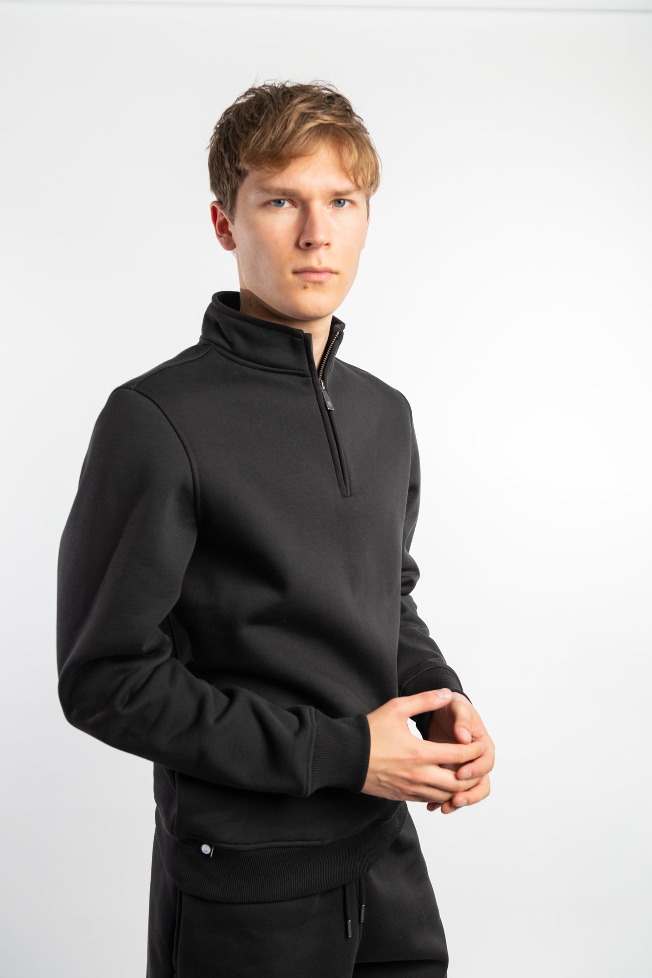 A man dresed very smart in a organic cotton 1/4 zip jumper from Pioneer Clothing in black. 