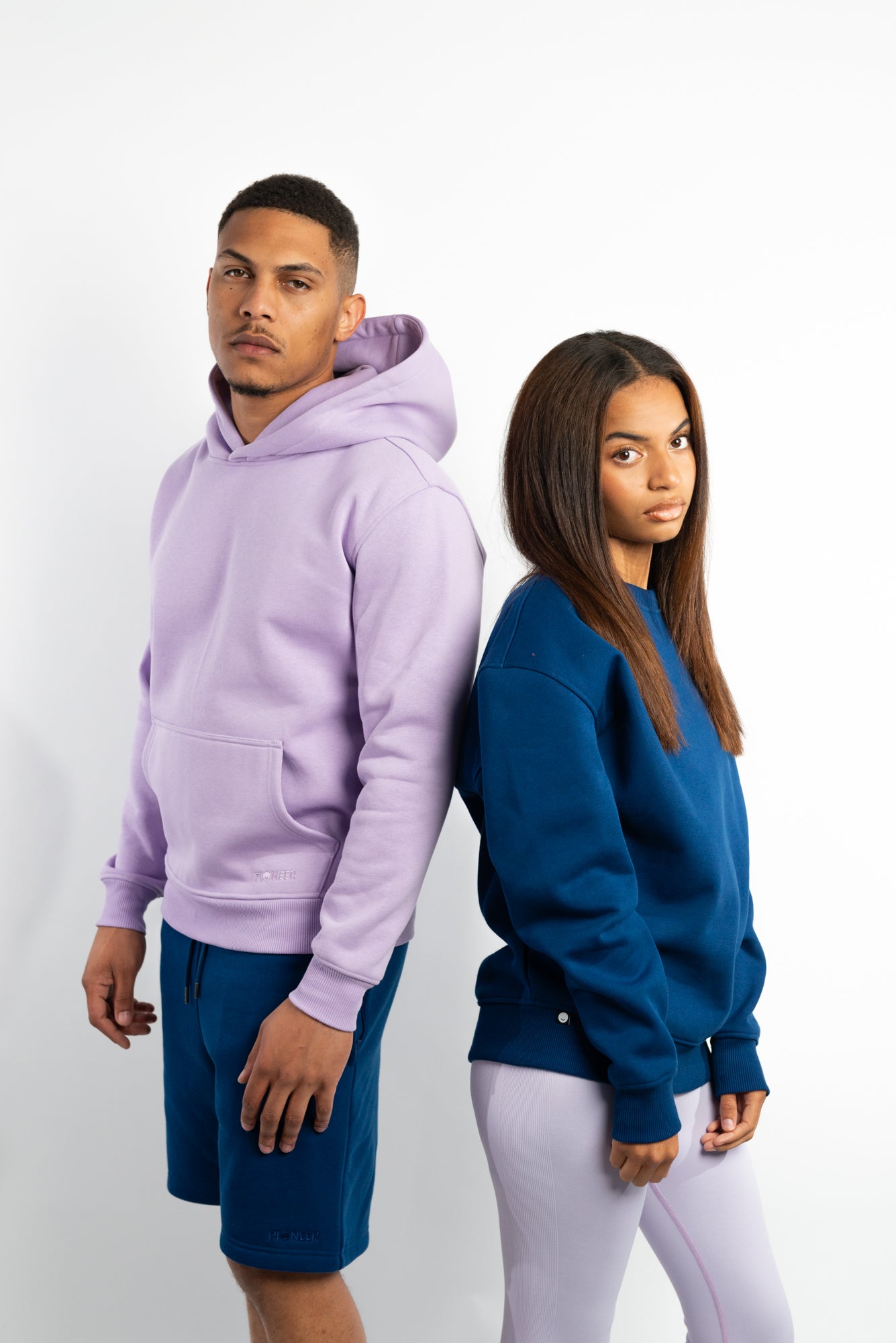 A couple in matching sustainable activewear and sweats in lilac and navy. Organic cotton crew necks and hoodies.