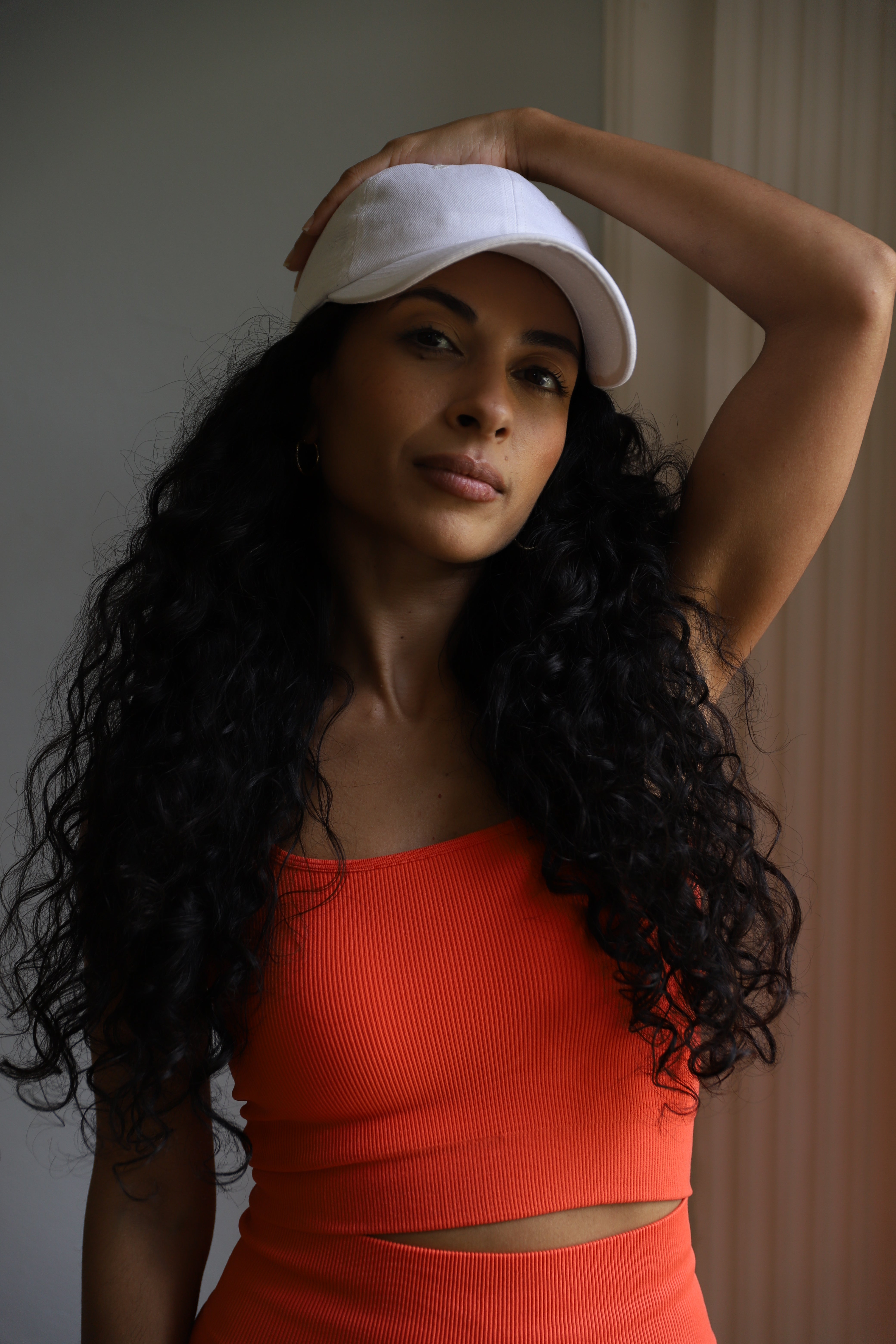 Image of model wearing Mandarin Red Seamless Cropped Vest Top along with matching colour leggings with her one hand on her head.