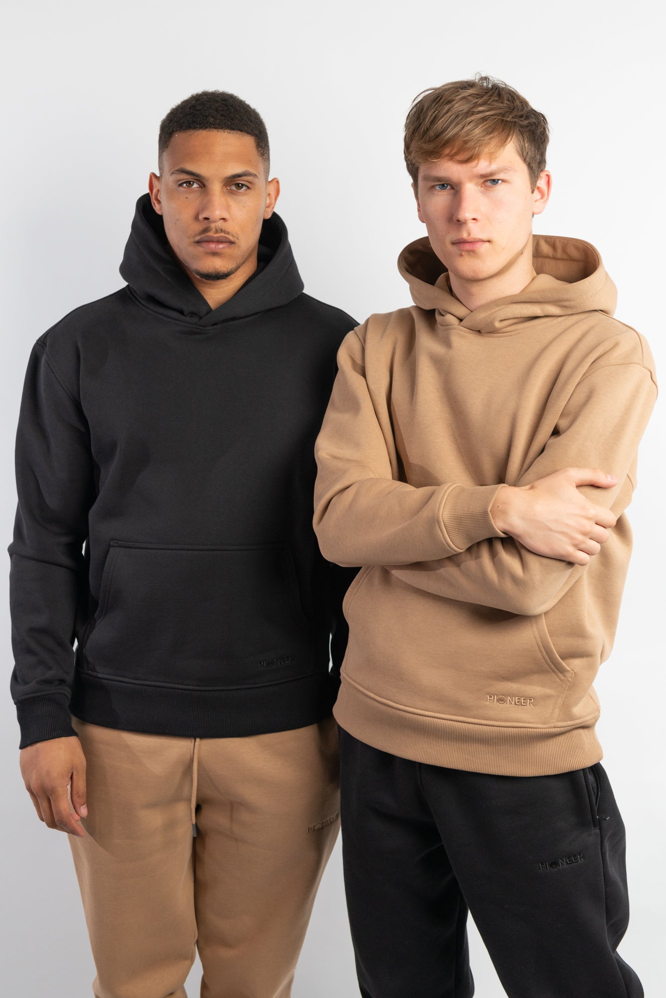 Two models standing front facing wearing Black and Hazelnut Hoodies
