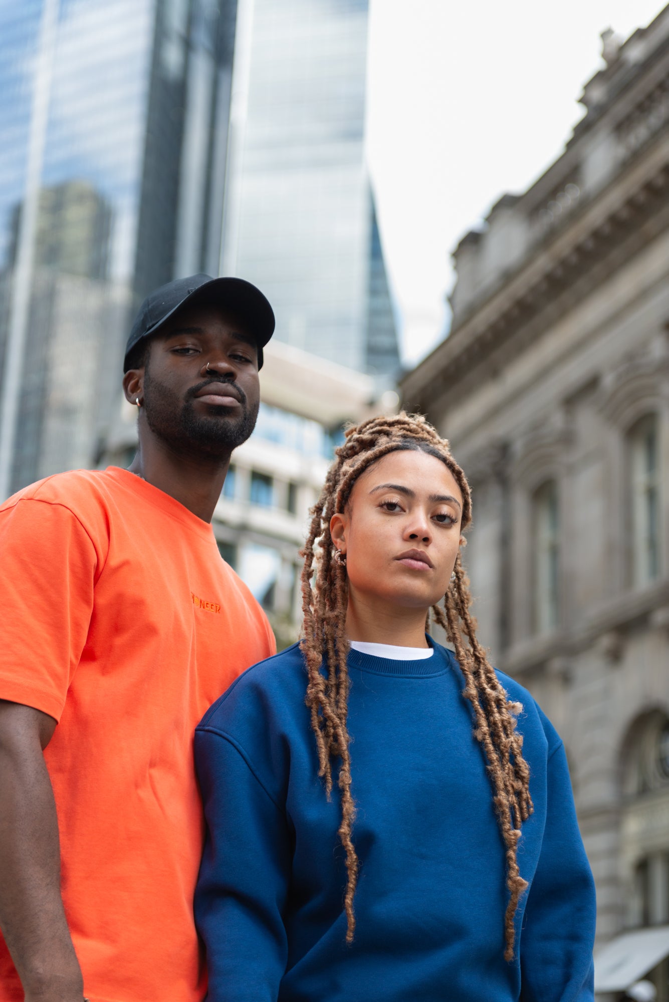 Male model wearing Mandarin Red Tshirt and Female model wearing Navy Crew New Sweatshirt posing in front of the building.