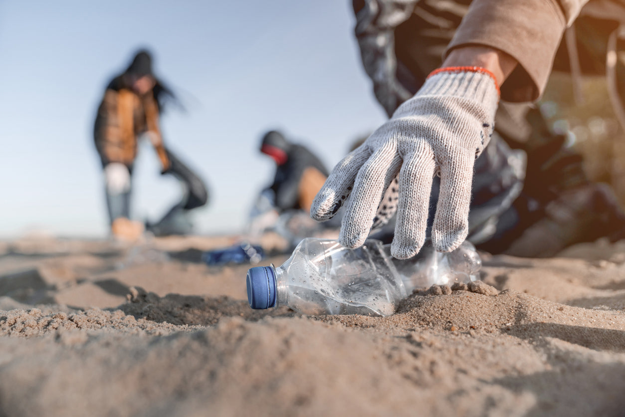 Man picking the plastic bottle from the beach.